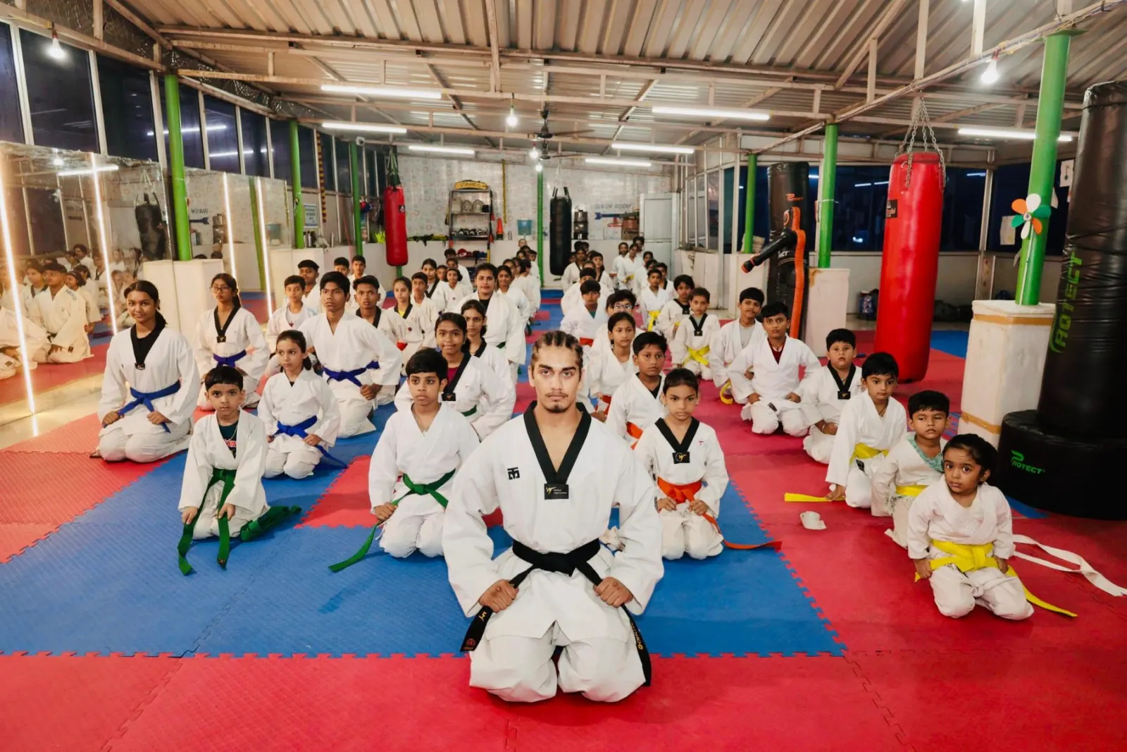 Students seated in rows on the mat with their coach at the front
